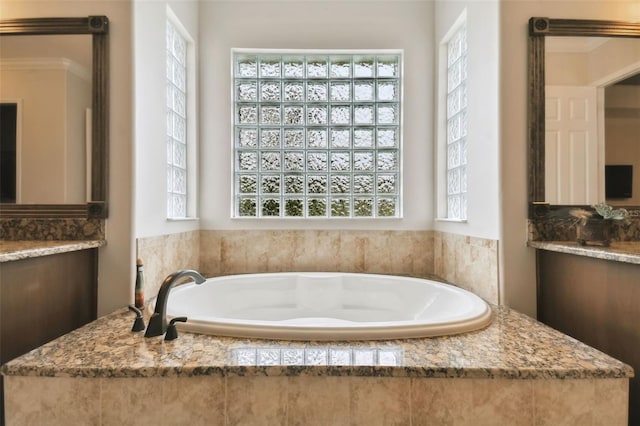 bathroom featuring plenty of natural light, vanity, and a relaxing tiled tub