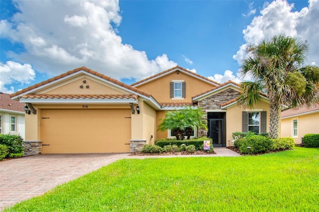 mediterranean / spanish-style house featuring a garage, stone siding, decorative driveway, stucco siding, and a front yard