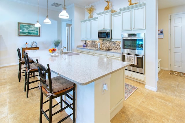 kitchen with an island with sink, crown molding, stainless steel appliances, and decorative backsplash