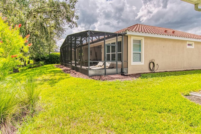 rear view of property with a lawn and a lanai