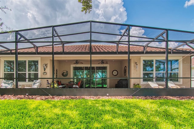 back of house with glass enclosure, a lawn, and ceiling fan