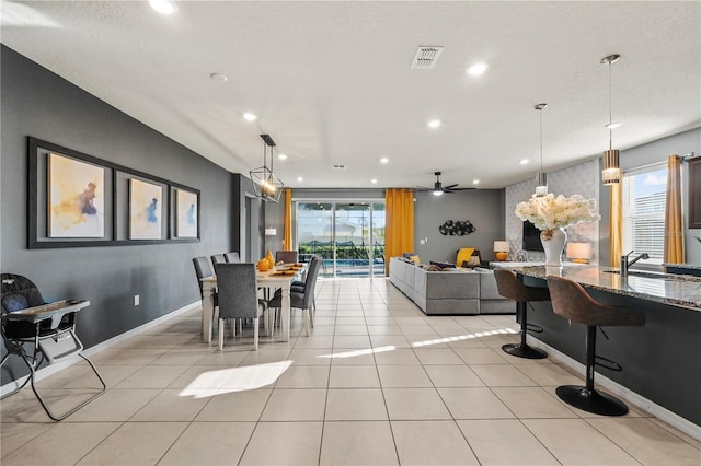 dining space featuring ceiling fan, a fireplace, a textured ceiling, and sink