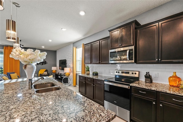 kitchen featuring light stone countertops, stainless steel appliances, a textured ceiling, and sink