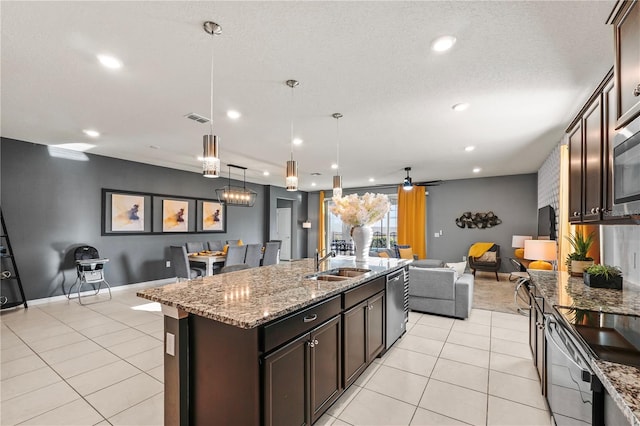 kitchen featuring dishwasher, decorative light fixtures, light stone countertops, an island with sink, and ceiling fan