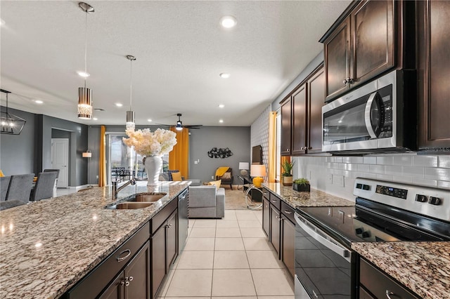 kitchen with light stone counters, hanging light fixtures, stainless steel appliances, and sink