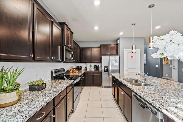 kitchen featuring light tile patterned floors, decorative light fixtures, stainless steel appliances, sink, and light stone countertops