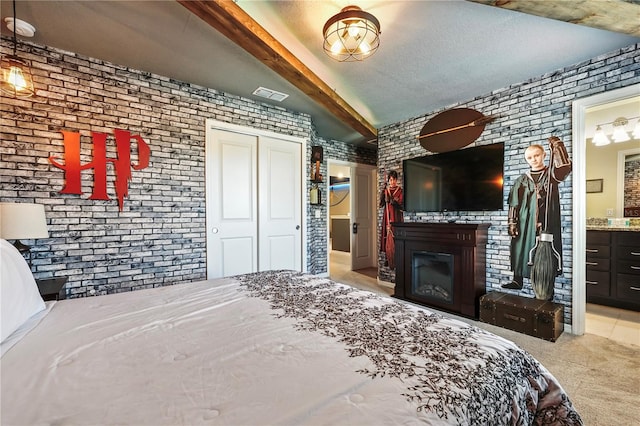 carpeted bedroom featuring ensuite bathroom, brick wall, beam ceiling, and a closet