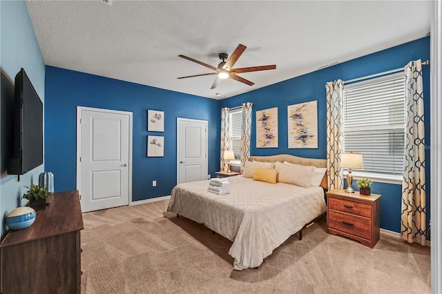 bedroom featuring a textured ceiling, ceiling fan, carpet floors, and multiple windows