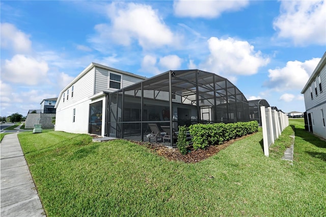 back of property featuring glass enclosure, a lawn, and a patio