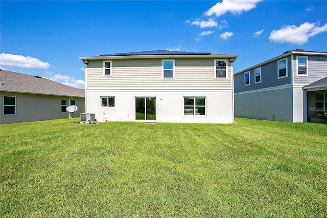 back of house featuring central AC unit and a lawn