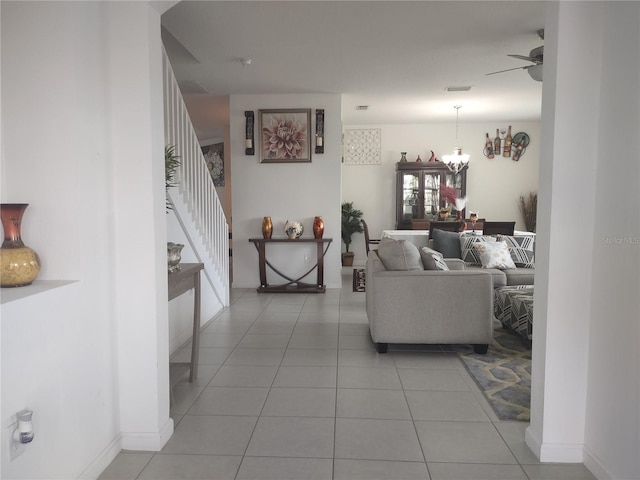 tiled living room featuring ceiling fan with notable chandelier