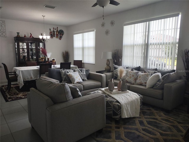 tiled living room featuring ceiling fan with notable chandelier