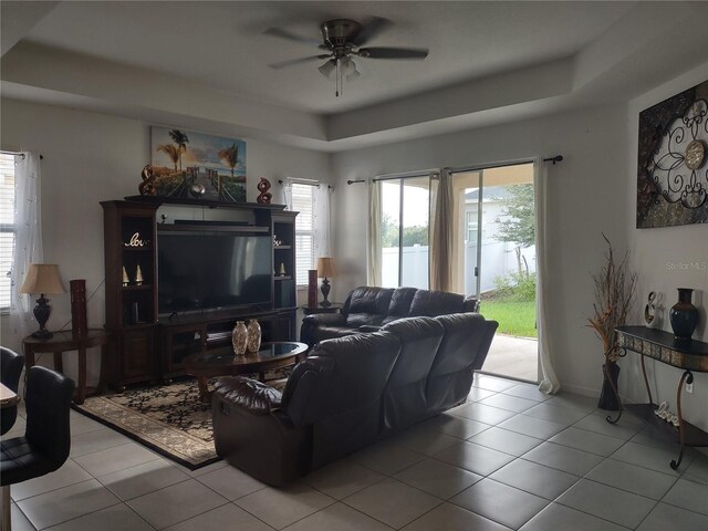 living room featuring a healthy amount of sunlight, ceiling fan, light tile patterned floors, and a tray ceiling