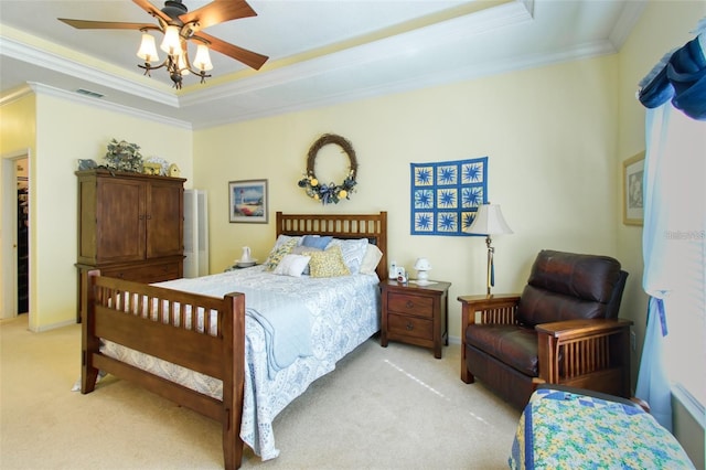 carpeted bedroom with ceiling fan, crown molding, and a tray ceiling