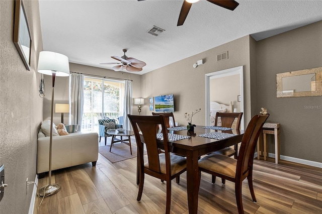 dining area with a textured ceiling, light hardwood / wood-style flooring, and ceiling fan