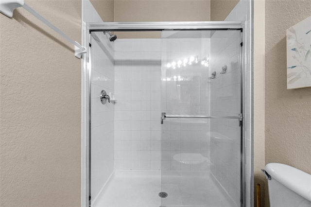 bathroom with a shower with shower door and toilet