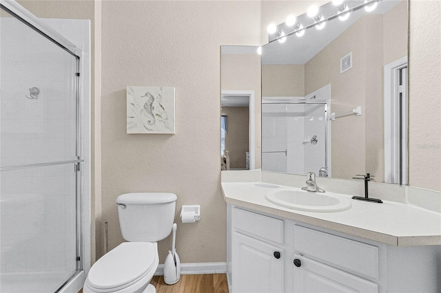 bathroom featuring a shower with shower door, toilet, vanity, and hardwood / wood-style flooring