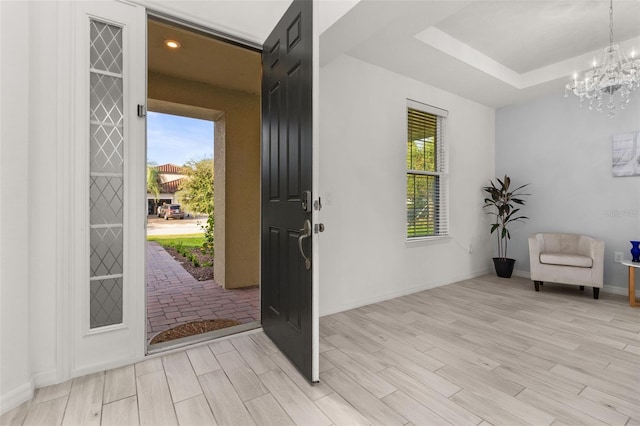 foyer entrance featuring plenty of natural light, a chandelier, and light hardwood / wood-style flooring