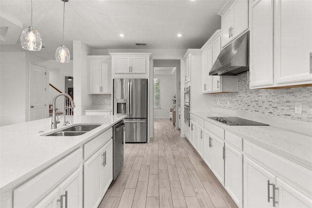 kitchen featuring sink, light hardwood / wood-style flooring, appliances with stainless steel finishes, decorative light fixtures, and white cabinetry