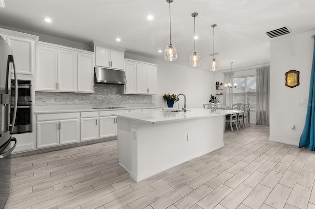 kitchen featuring white cabinetry, sink, hanging light fixtures, light hardwood / wood-style flooring, and an island with sink