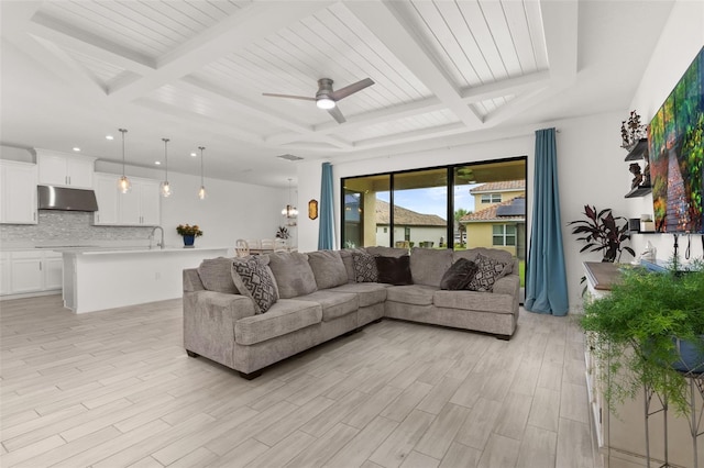 living room with beamed ceiling, light hardwood / wood-style floors, ceiling fan, and sink