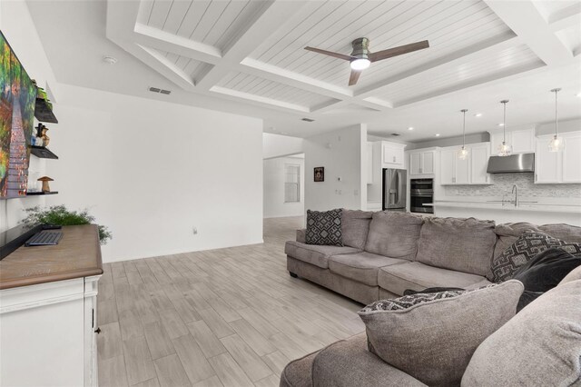 living room with ceiling fan, sink, beamed ceiling, and light hardwood / wood-style floors