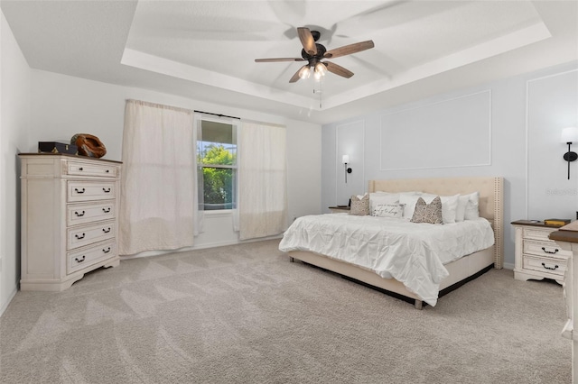 carpeted bedroom featuring a raised ceiling and ceiling fan