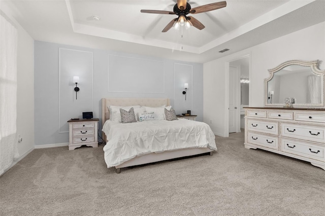 carpeted bedroom featuring a tray ceiling and ceiling fan