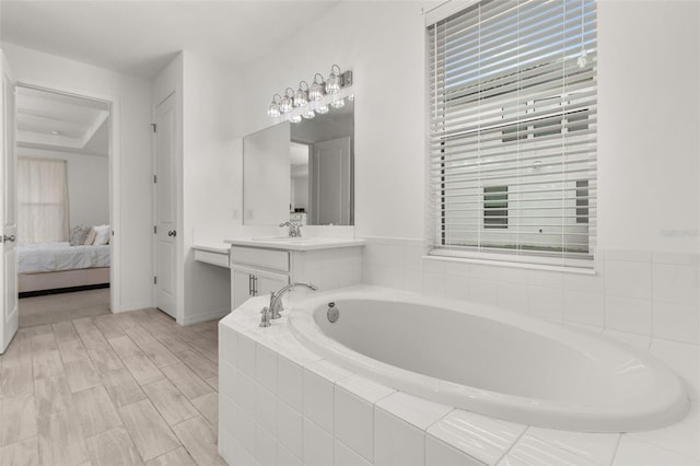 bathroom featuring tiled bath, vanity, and wood-type flooring