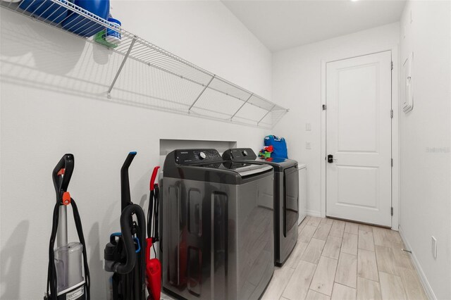 washroom with washing machine and dryer and light hardwood / wood-style floors