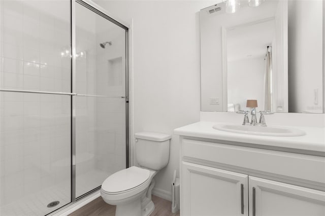 bathroom with an enclosed shower, vanity, toilet, and wood-type flooring