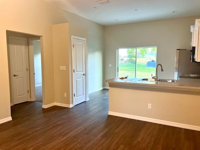 kitchen featuring sink, stainless steel refrigerator, white cabinetry, and dark wood-type flooring