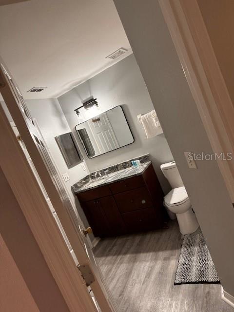 bathroom featuring vanity, toilet, and hardwood / wood-style flooring