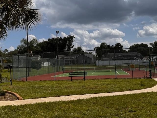 view of tennis court featuring a lawn