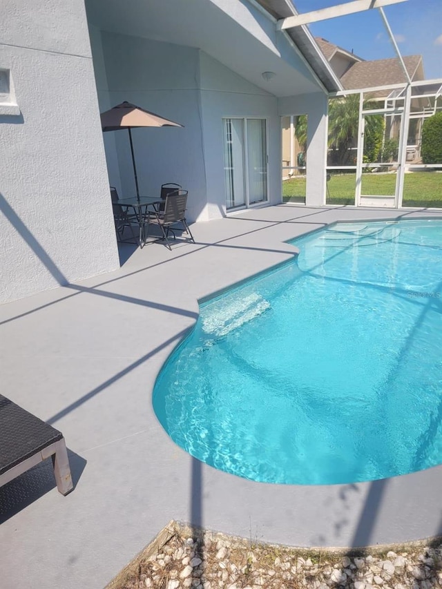 view of pool with glass enclosure and a patio area