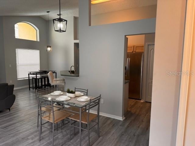 dining room with dark wood-type flooring and vaulted ceiling