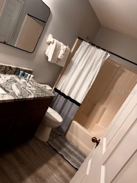 full bathroom with wood-type flooring, shower / tub combo with curtain, vanity, and toilet