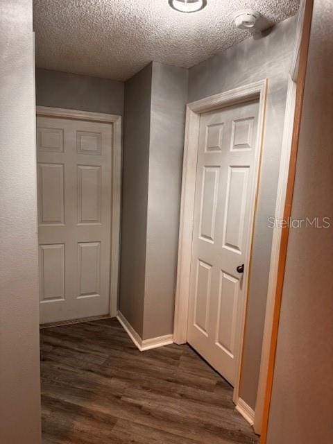 corridor with a textured ceiling and dark hardwood / wood-style flooring