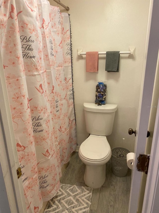 bathroom with toilet and a shower with shower curtain