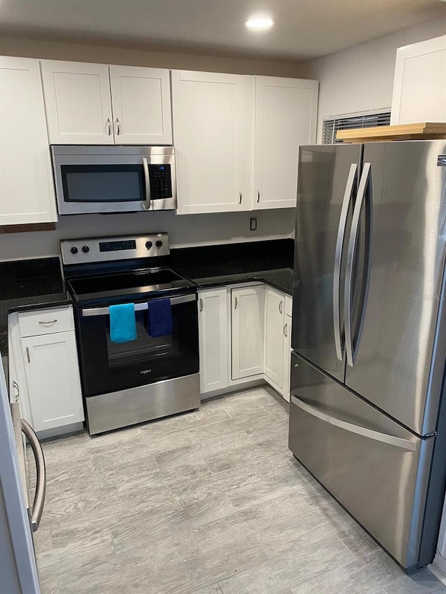 kitchen with appliances with stainless steel finishes, light hardwood / wood-style floors, and white cabinetry