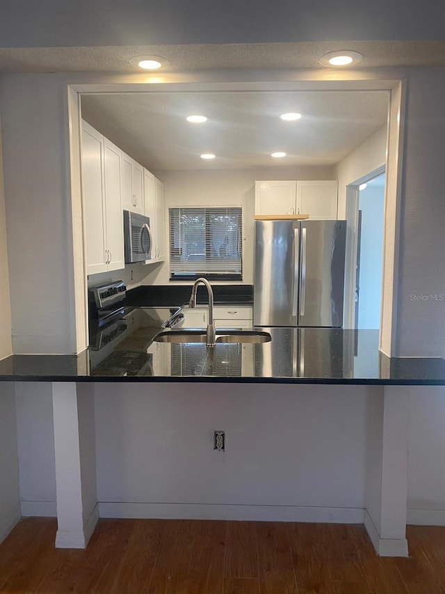 2647 Surrey Ct Unit 2647, Kissimmee, FL 34741 - kitchen with dark stone countertops, dark wood finished floors, white cabinets, a peninsula, and appliances with stainless steel finishes
