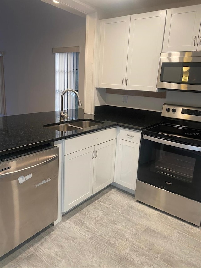 2647 Surrey Ct Unit 2647, Kissimmee, FL 34741 - kitchen with white cabinets, dark stone countertops, a sink, and stainless steel appliances