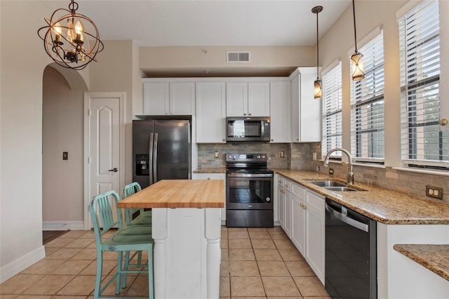 kitchen with visible vents, decorative backsplash, appliances with stainless steel finishes, wood counters, and a sink