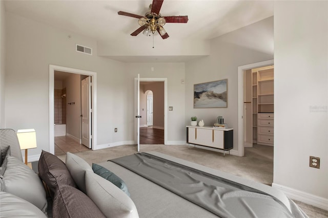 bedroom with visible vents, ensuite bath, baseboards, light colored carpet, and a spacious closet