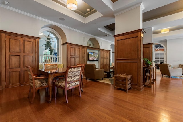 dining space with visible vents, ornamental molding, a tray ceiling, wood finished floors, and arched walkways