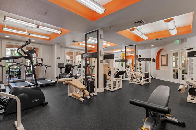 exercise room with a raised ceiling, french doors, visible vents, and baseboards