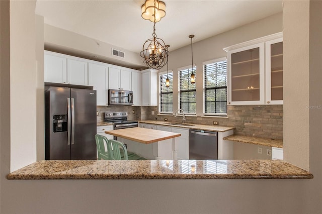 kitchen featuring visible vents, a sink, tasteful backsplash, white cabinetry, and appliances with stainless steel finishes