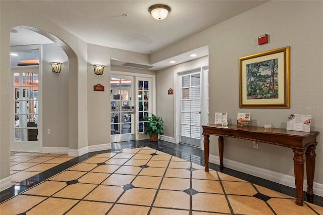 foyer entrance featuring tile patterned floors, baseboards, recessed lighting, french doors, and arched walkways