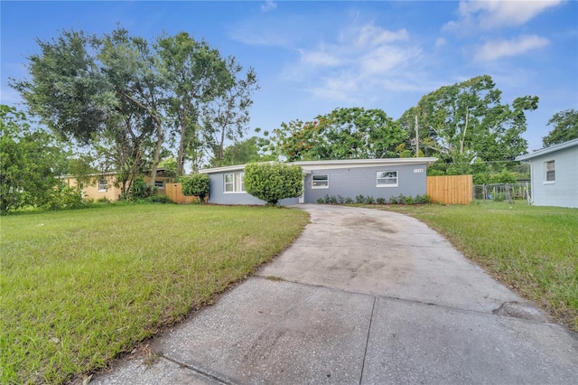 ranch-style home featuring a front yard, concrete driveway, and fence