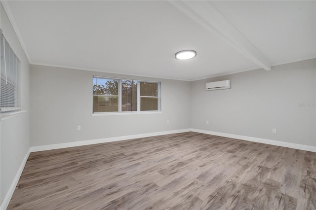 spare room with a wall unit AC, light hardwood / wood-style floors, and beamed ceiling